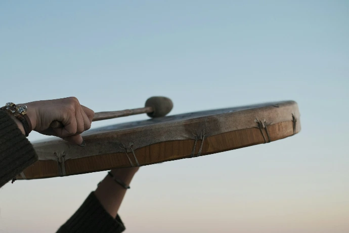 person holding brown wooden mallet and drum