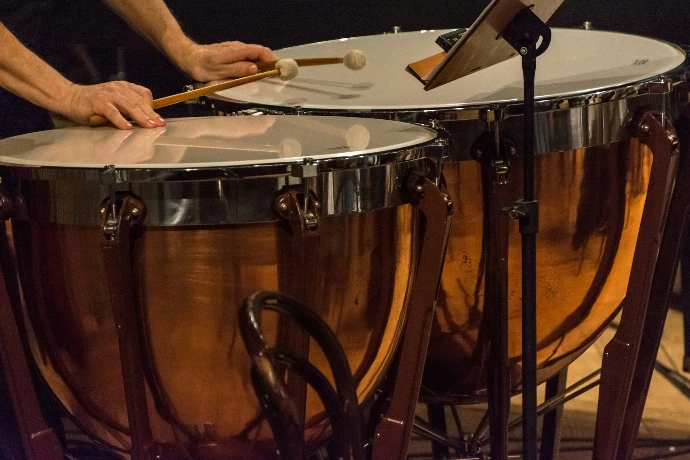 person holding mallets in front of timpani
